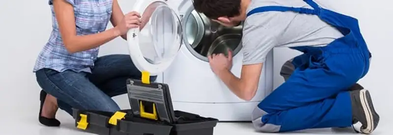 Washer repair technician inspecting a front-load washing machine with tools in Los Angeles, CA