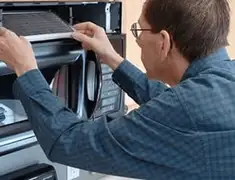 Appliance repair technician replacing a microwave vent filter in Los Angeles, CA