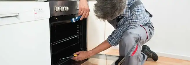 Oven repair technician inspecting and servicing an electric oven in Los Angeles, CA