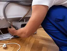 Appliance repair technician fixing refrigerator water line and connections in Los Angeles, CA