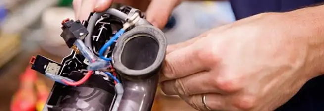 Vacuum repair technician reconnecting wiring and components in Los Angeles, CA