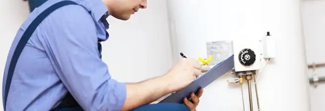 Water heater repair technician inspecting the unit and recording service notes in Los Angeles, CA